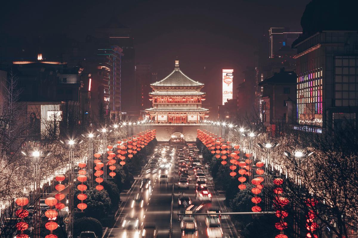 Xi'an Bell Tower illuminated at night with red lanterns lining the boulevard and car light trails on Nandajie — the Zhonglou China Mobile flagship store is a five-minute walk from this landmark