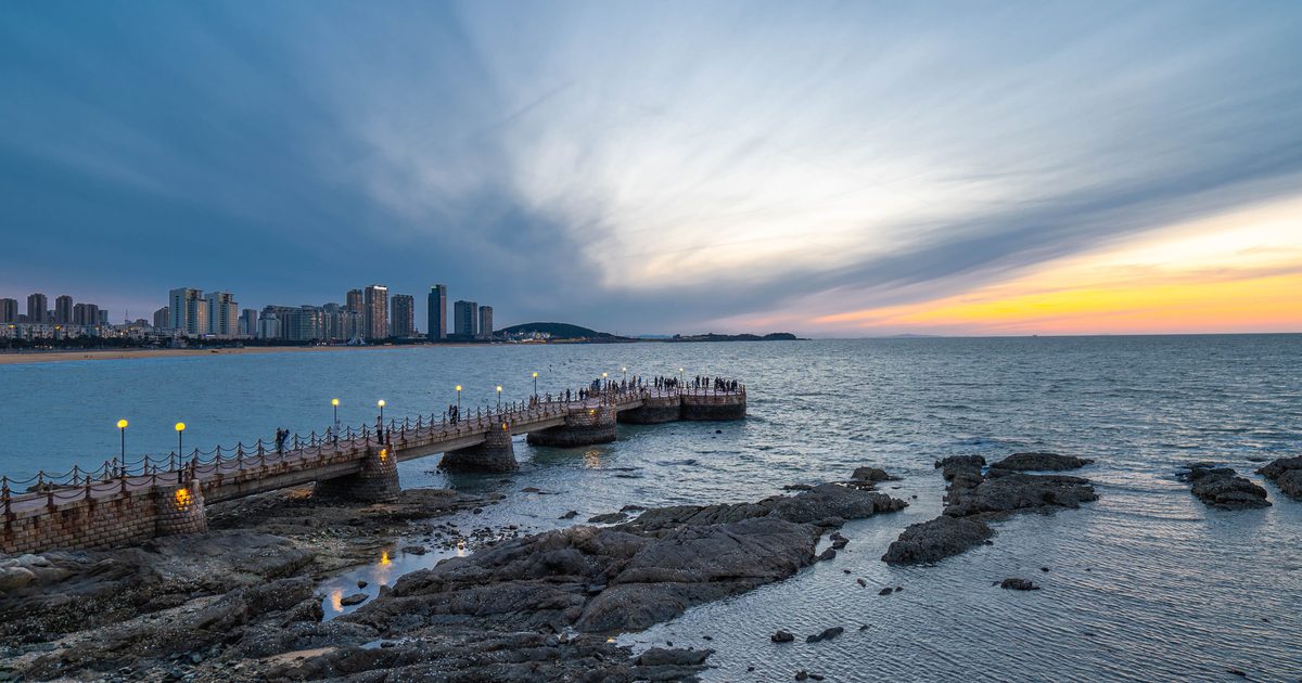 Sunset view of Qingdao's Zhanqiao Pier with the city skyline, Shandong province, China